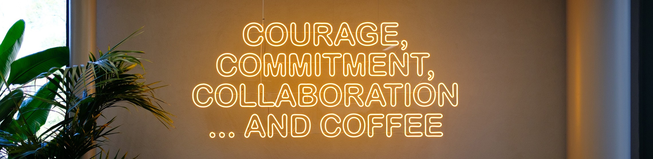 Neonkyltti toimistossa tekstillä Courage, Commitment, Collaboration and Coffee