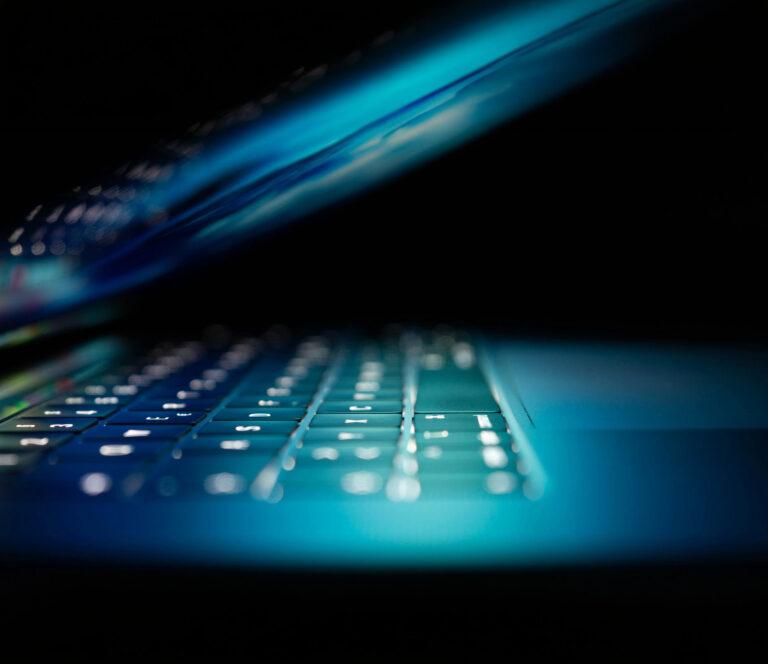 Sinisävyinen lähikuva kannettavan tietokoneen näppäimistöstä. Kuva symboloi kyberturvallisuutta, digitaalista työympäristöä ja tietojärjestelmien suojaamista